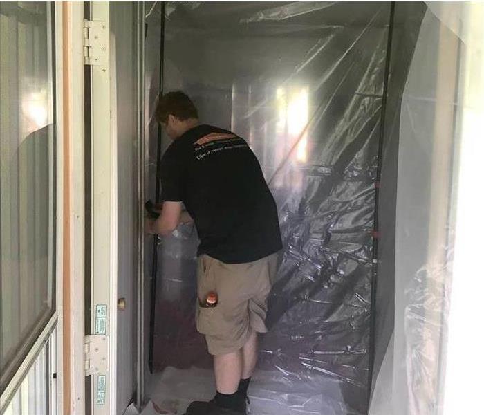 SERVPRO employee putting up Containment